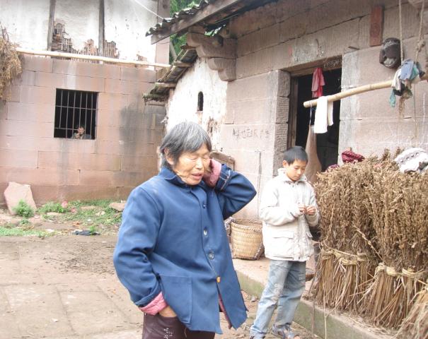 何辉辉与无奈的婆婆站在院子里，他的妈妈还在屋子里张望着.jpg