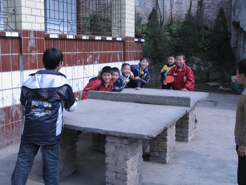 小朋友们在石台做的乒乓台上打乒乓球
